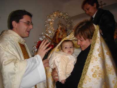 Los niños recien nacidos son pasados bajo el manto de la Virgen